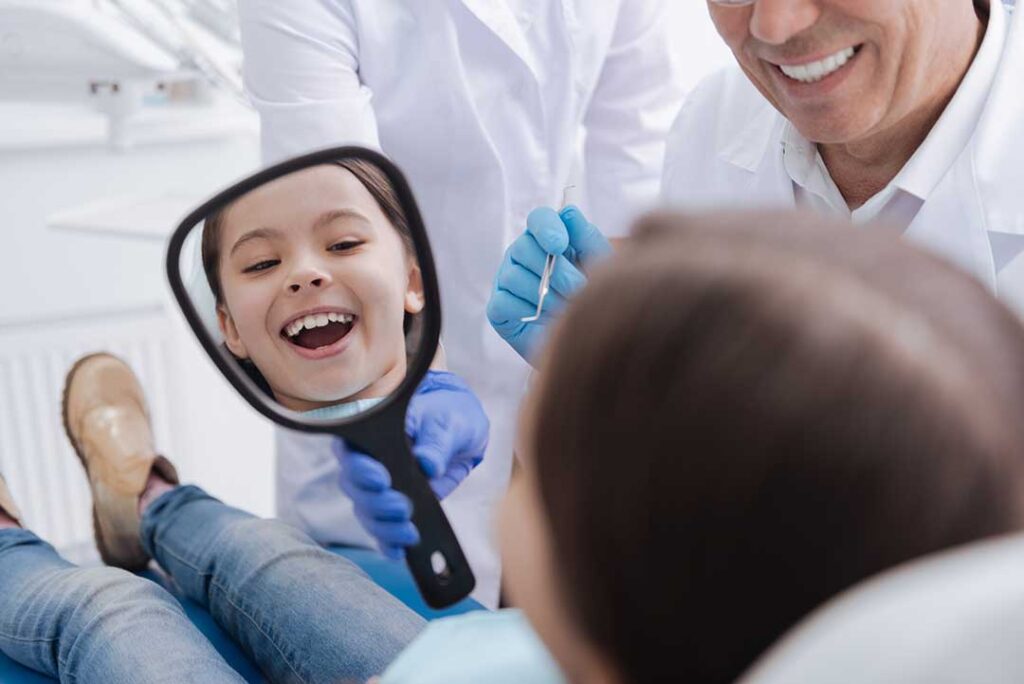 Person brushing teeth and cleaning their tongue at a bathroom sink with floss and a glass of water nearby