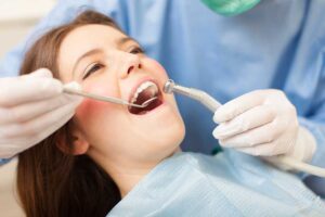A person applying whitening strips to their teeth in a bright, clean bathroom setting.