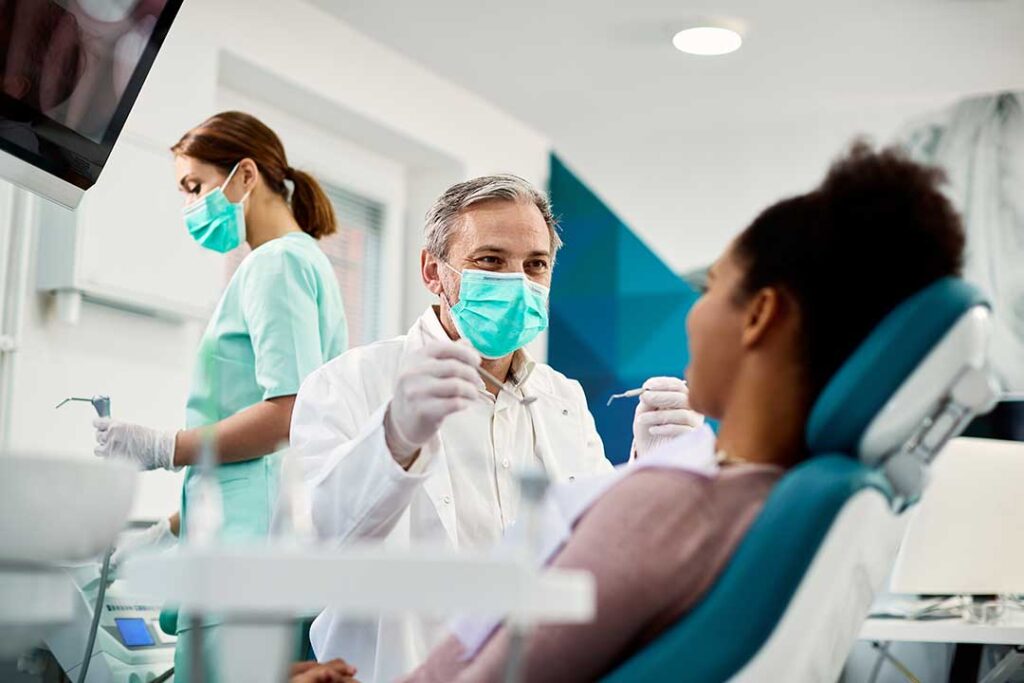 A toddler sits calmly on a parent's lap while a dental professional gently examines the child's mouth.