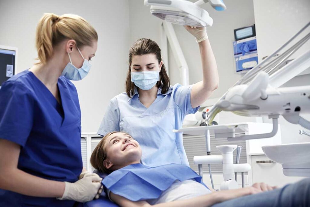 Person gently guiding dental floss between teeth in front of a bathroom mirror. KEYWORDS: ["proper flossing technique", "dental floss between teeth", "oral hygiene routine"]